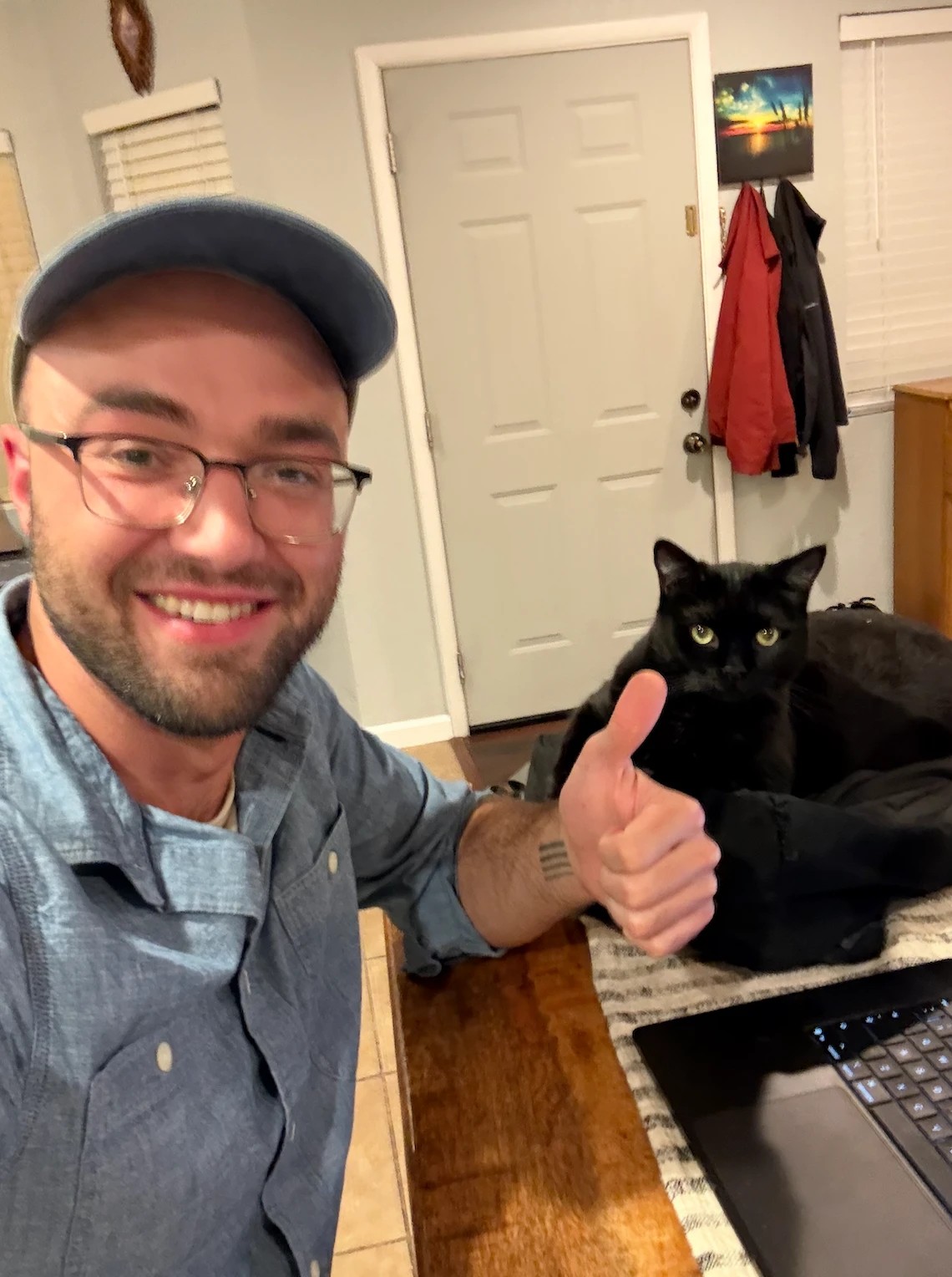 Carter giving a thumbs up at his laptop, with his black cat