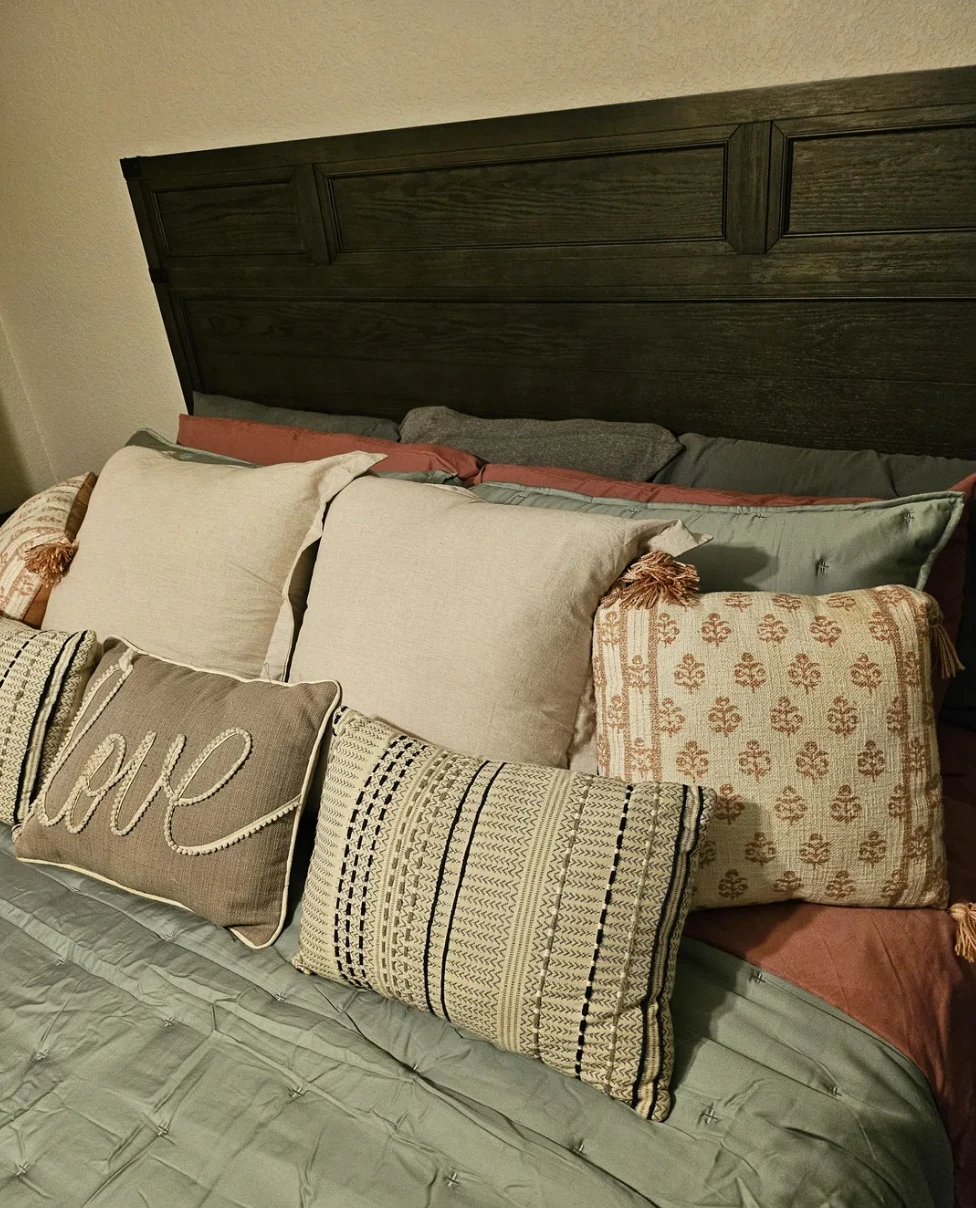 A bed headboard piled with decorative pillows