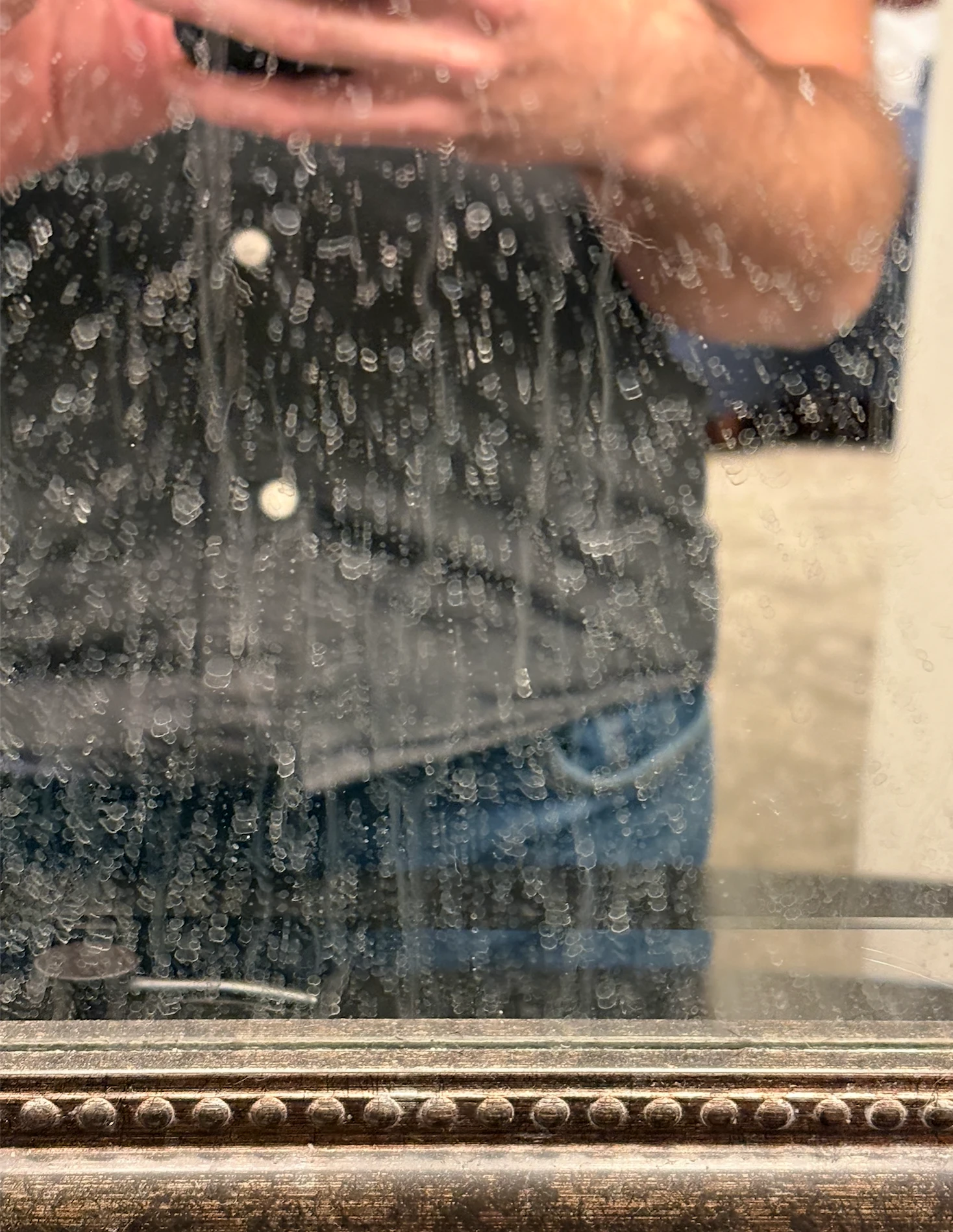 Hand wiping steam off a bathroom mirror